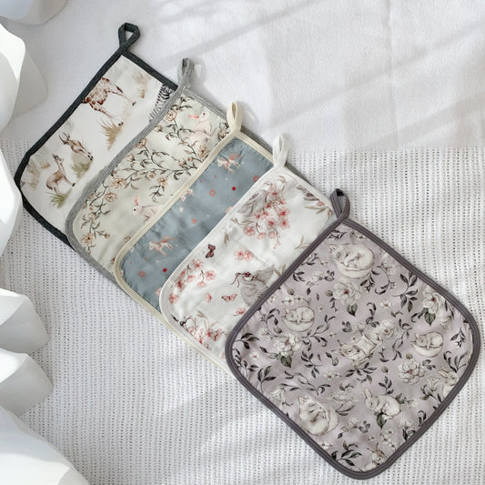 Set of four floral patterned pot holders on a white surface