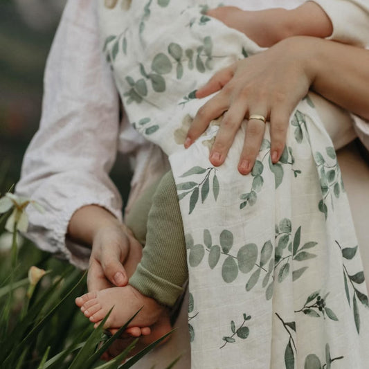 Close-up of a person holding a child's hand with a floral-patterned garment.